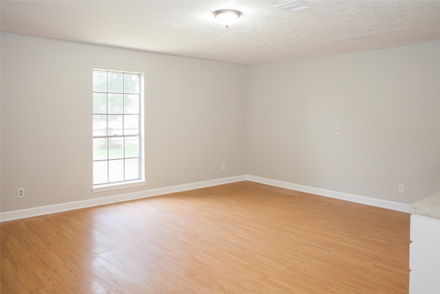 unfurnished room with a textured ceiling and light hardwood / wood-style flooring