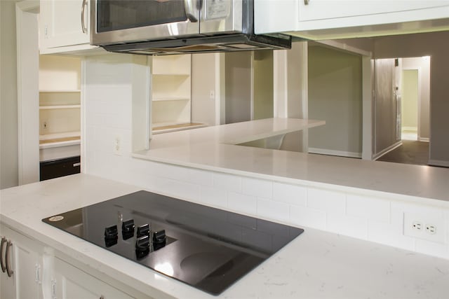 kitchen with white cabinetry, black electric cooktop, and light stone countertops