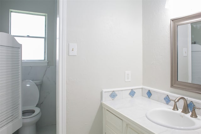 bathroom with a healthy amount of sunlight, toilet, and vanity