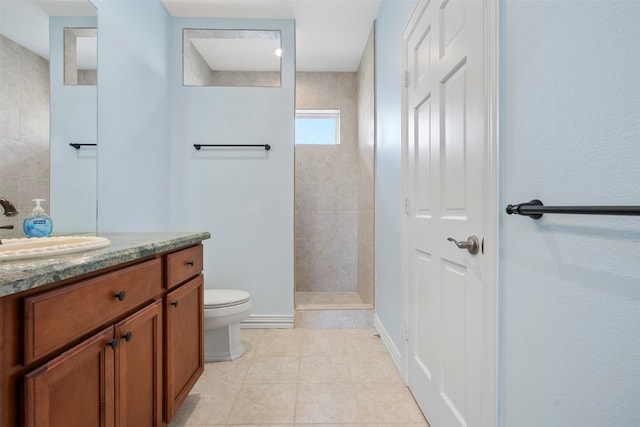 bathroom with vanity, tile patterned flooring, toilet, and tiled shower