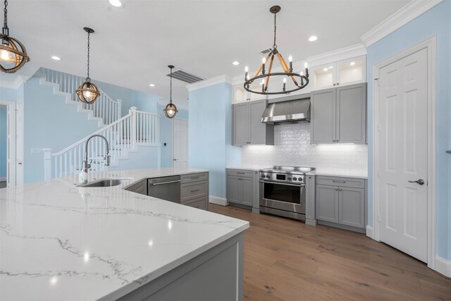 kitchen with wood-type flooring, appliances with stainless steel finishes, decorative light fixtures, and sink