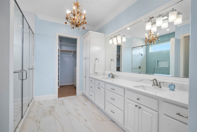 bathroom with ornamental molding, vanity, an inviting chandelier, and a shower with shower door