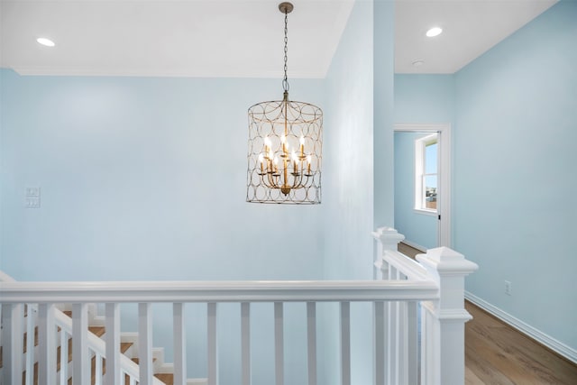 stairs with hardwood / wood-style floors and an inviting chandelier