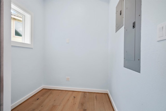 spare room with electric panel, baseboards, and wood finished floors