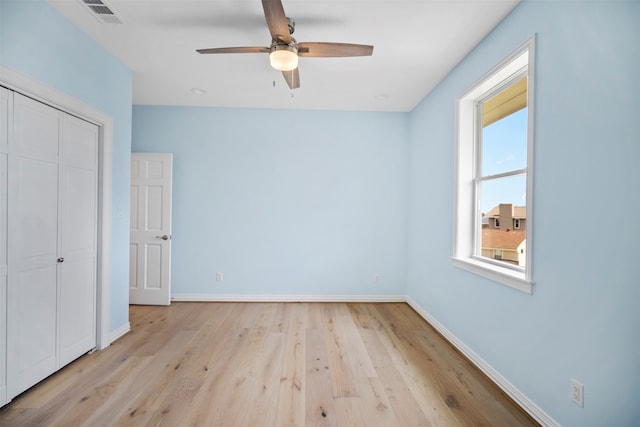 unfurnished bedroom featuring multiple windows, light wood-type flooring, ceiling fan, and a closet