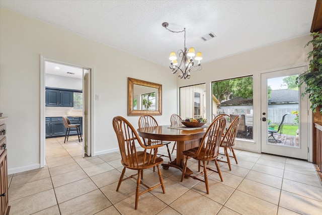 tiled dining room with a wealth of natural light, a notable chandelier, and a textured ceiling