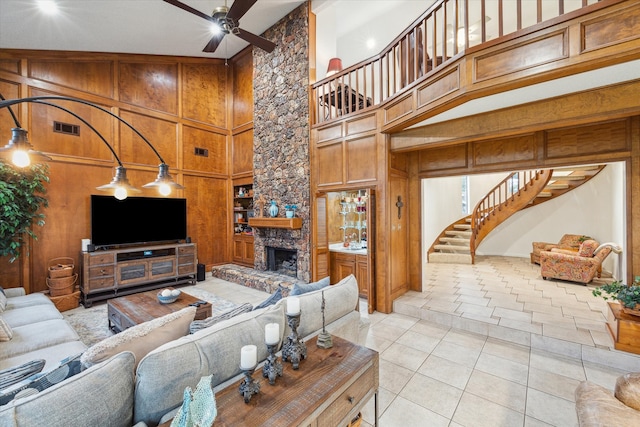 tiled living room with wooden walls, high vaulted ceiling, a fireplace, and ceiling fan