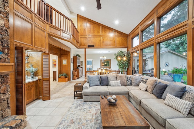 tiled living room featuring high vaulted ceiling and ceiling fan with notable chandelier