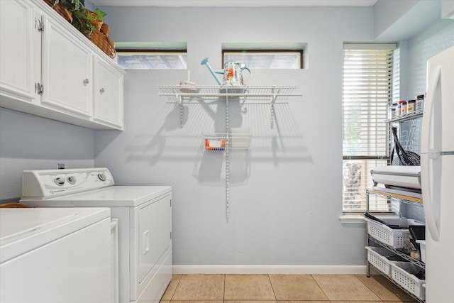 laundry area featuring washer and clothes dryer, cabinets, and light tile floors