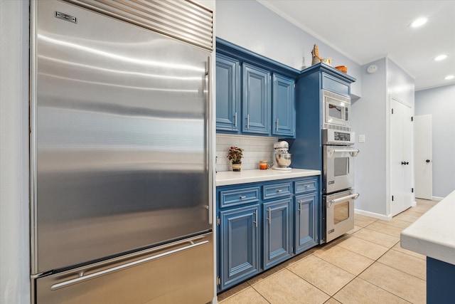 kitchen featuring blue cabinetry, tasteful backsplash, light tile flooring, and built in appliances