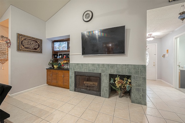 living room with a tiled fireplace, a textured ceiling, and light tile floors