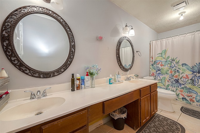 bathroom featuring double sink vanity, tile flooring, a textured ceiling, and toilet