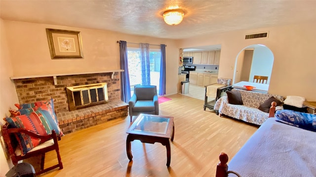 living room with light wood-type flooring and a brick fireplace