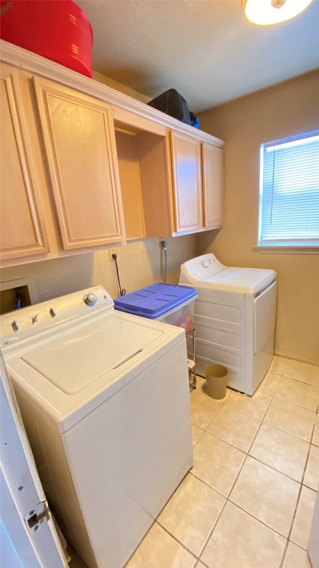 washroom with cabinets, hookup for a washing machine, light tile flooring, and washing machine and clothes dryer