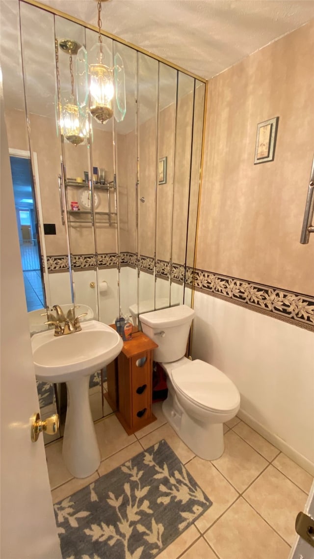 bathroom featuring a notable chandelier, tile flooring, toilet, and a textured ceiling