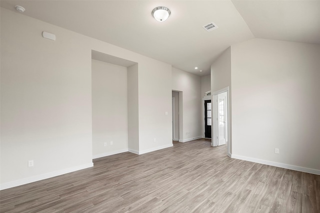 empty room with light hardwood / wood-style flooring and lofted ceiling