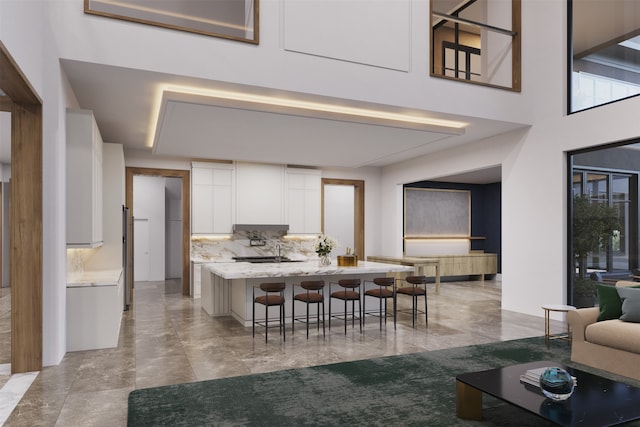 kitchen with white cabinetry, a center island, light stone countertops, a kitchen bar, and decorative backsplash