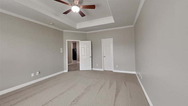 spare room featuring ceiling fan, a tray ceiling, carpet floors, and crown molding