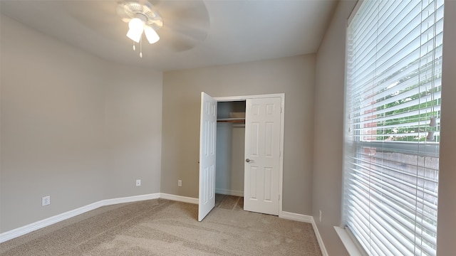 unfurnished bedroom with light carpet, a closet, and ceiling fan