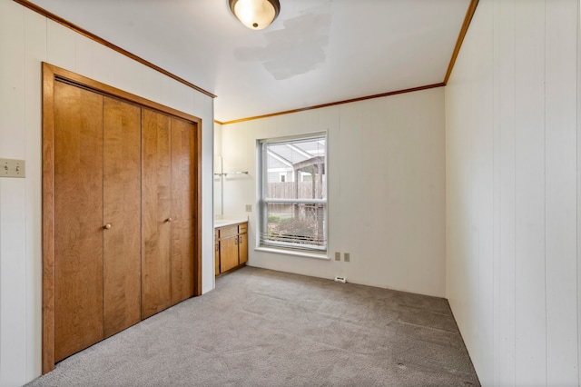 unfurnished bedroom with a closet, crown molding, and carpet flooring