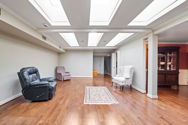 living area with ornamental molding, hardwood / wood-style flooring, and a skylight