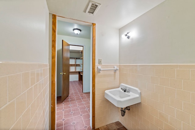 bathroom featuring tile walls, tile floors, and sink