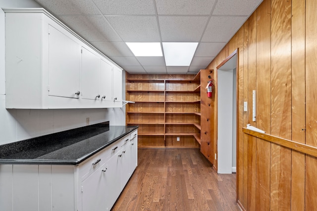 kitchen with white cabinets, wood-type flooring, and a paneled ceiling