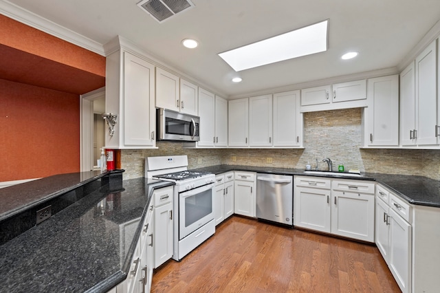 kitchen featuring wood-type flooring, backsplash, sink, white cabinetry, and appliances with stainless steel finishes