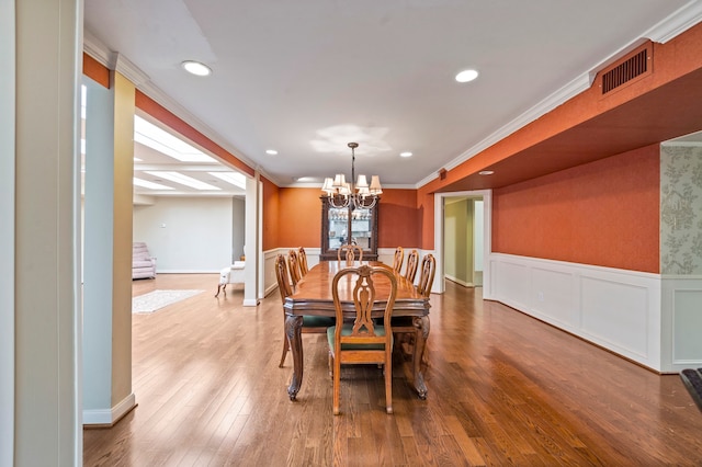 dining area with beam ceiling, an inviting chandelier, ornamental molding, and wood-type flooring