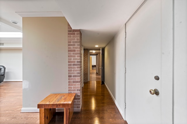 corridor with hardwood / wood-style floors and brick wall