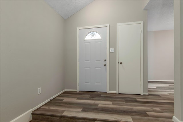 entryway featuring lofted ceiling, wood-type flooring, and a textured ceiling