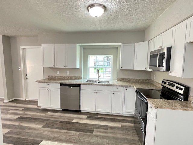 kitchen featuring white cabinetry, stainless steel appliances, wood-type flooring, and sink