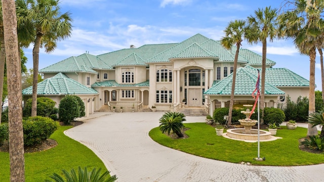 mediterranean / spanish house featuring a tiled roof, a front lawn, decorative driveway, and stucco siding