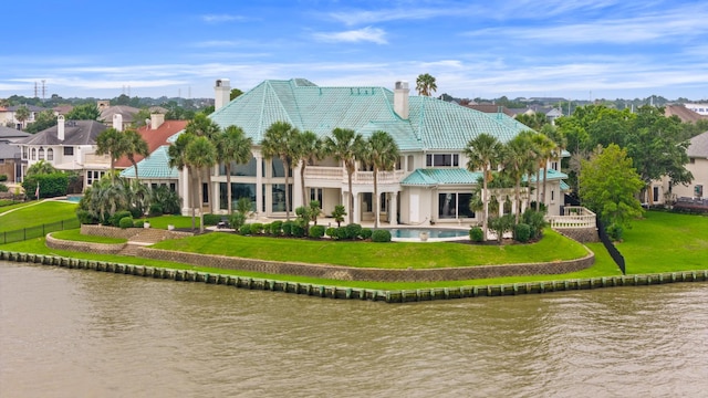 back of house with a lawn and a water view