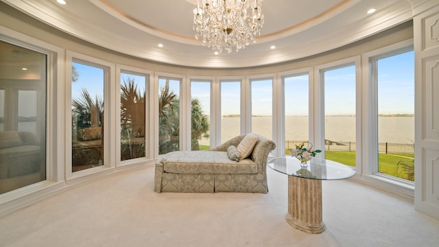 sunroom / solarium featuring a water view, a notable chandelier, and a tray ceiling