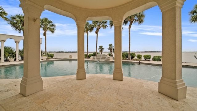 view of pool with a pool with connected hot tub, a patio area, and a water view