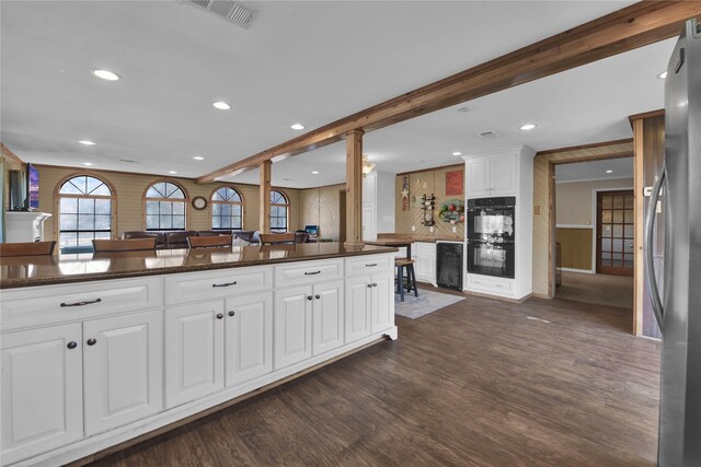 kitchen with stainless steel refrigerator, black double oven, dark hardwood / wood-style floors, backsplash, and white cabinetry