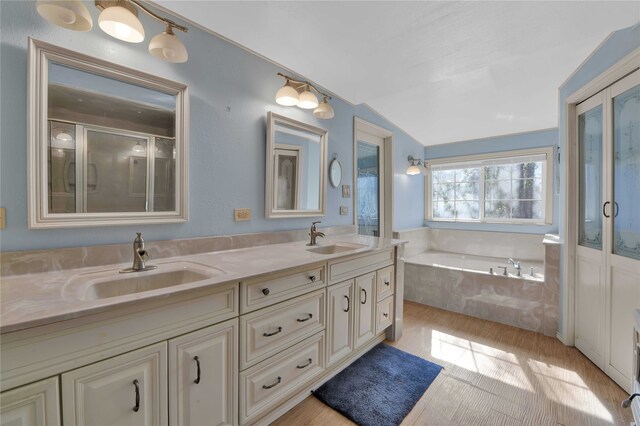 bathroom with shower with separate bathtub, hardwood / wood-style floors, lofted ceiling, and double sink vanity