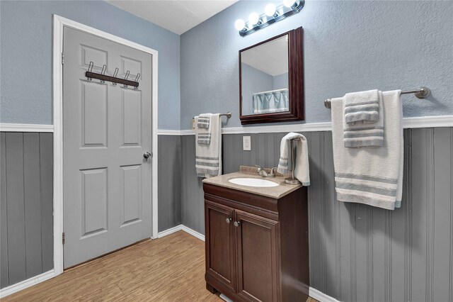 bathroom with vanity with extensive cabinet space and hardwood / wood-style flooring