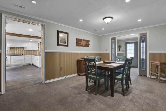 carpeted dining space featuring ornamental molding