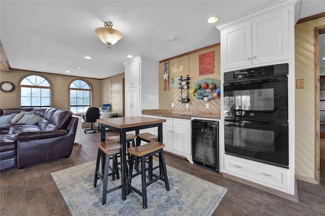 kitchen featuring black double oven, wine cooler, dark hardwood / wood-style flooring, and white cabinets