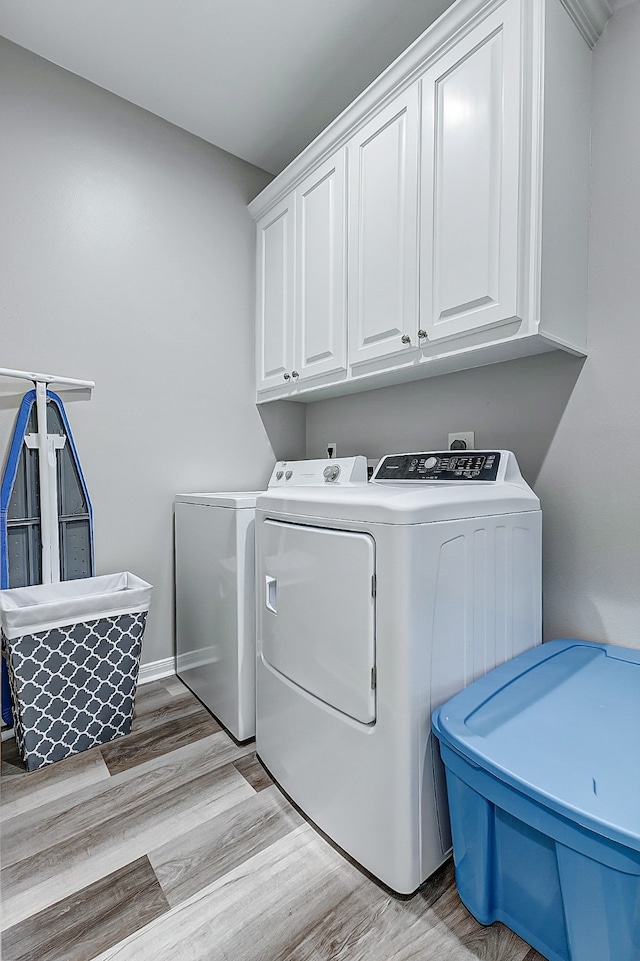 washroom with washing machine and dryer, light hardwood / wood-style flooring, hookup for an electric dryer, and cabinets