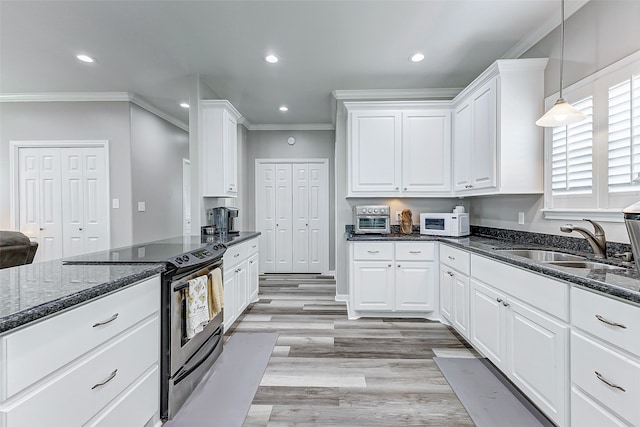 kitchen with electric range oven, dark stone counters, white cabinets, and pendant lighting