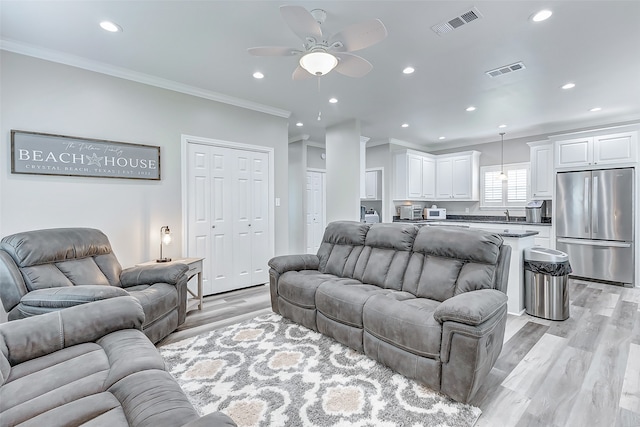 living room with ceiling fan, ornamental molding, and light hardwood / wood-style floors