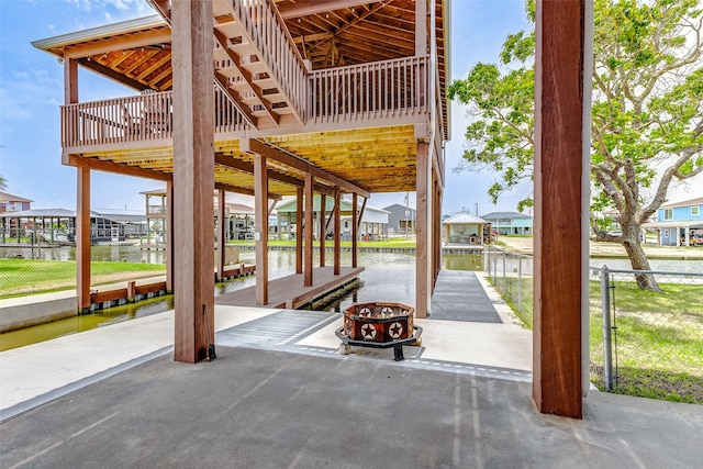 view of patio with a boat dock, a water view, and a fire pit