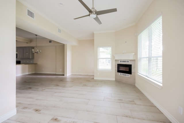 unfurnished living room featuring light hardwood / wood-style floors, a tile fireplace, and ceiling fan with notable chandelier