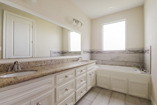 bathroom with a tub, a wealth of natural light, and double vanity