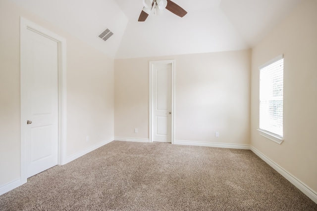 carpeted spare room featuring vaulted ceiling and ceiling fan