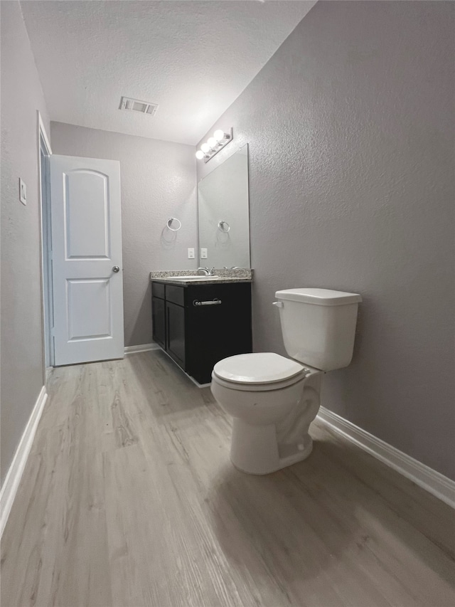 bathroom featuring vanity, a textured ceiling, toilet, and hardwood / wood-style floors