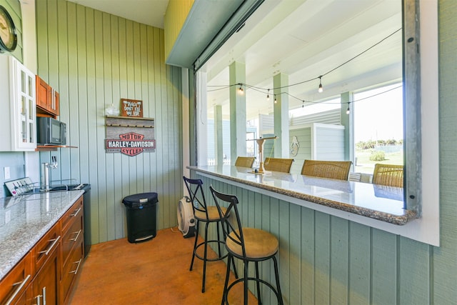 bar featuring wooden walls and light stone counters